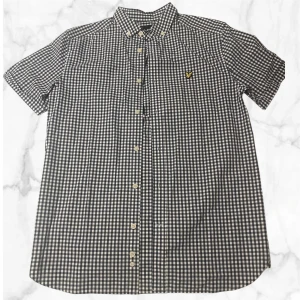 Rutig kortärmad skjorta Lyle & Scott - Använd para ett par få gånger. Säljer på grund av att den helt enkelt inte passar mig längre. Snygg kortärmad skjorta från Lyle & Scott i klassiskt rutigt mönster, blå och vit. Skjortan har button-down krage, knappar hela vägen och den ikoniska gula fågeln broderad på bröstet. Perfekt för dig som gillar stilrena och tidlösa plagg. 