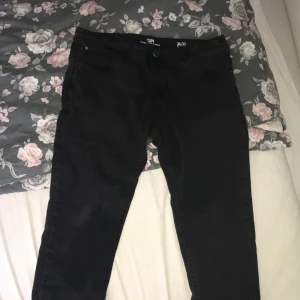 Svarta jeansbyxor från CSBV 34/32 - Svarta jeansbyxor från CSBV Original Denim Company i storlek 34/32. Klassisk femficksmodell med smalare ben och normal passform. Snygga svarta sömmar och stilren look, perfekta till en streetinspirerad outfit.
