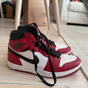  Jordan 1.5 Chicago (2015) Retro - Säljer ett par Nike Air Jordan 1 i klassiska Chicago-färgerna röd, vit och svart. Skorna har högt skaft, svart swoosh, svarta skosnören och perforerad tå. Tillverkade i skinn med vadderad häl och ikonisk Air Jordan-logga på sidan. Mycket bra skick, köpt i Kanada, kan skickas eller hämtas :)