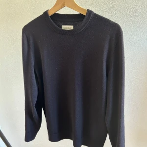 Blå merinoullströja These Glory Days - En stilren blå tröja från These Glory Days i mjuk och lyxig merinoull. Klassisk rund halsringning och långärmad modell, perfekt för lager-på-lager under kyliga dagar. Enkel och tidlös design som funkar till allt.