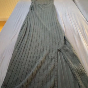 Svart ribbad långklänning med slits - Säljer en svart långklänning med ribbat mönster och snygg slits på sidan. Klänningen är ärmlös och har en figurnära passform som framhäver siluetten. Perfekt för dig som gillar stilrena och enkla plagg med en twist. Ettiket saknas