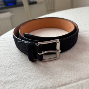 Marinblått skärp i mocka - Marinblått bälte i mocka med silverfärgat metallspänne. Aldrig använt. Passar storlek s. Sååå snyggt till jeans och en vit tshirt🥵