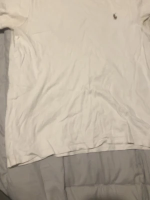 Vit slim fit t-shirt från Polo Ralph Lauren - Säljer en vit t-shirt från Polo Ralph Lauren i custom slim fit. Klassisk design med den ikoniska broderade polospelaren på bröstet. Tillverkad i mjuk bomull och passar perfekt till jeans eller shorts.