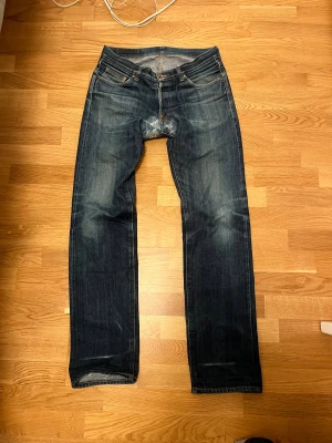 Edwin selvedge jeans - Edwin jeans i selvedge denim med slitningar och lagningar vid benslut och gren. Rak passform, fem fickor och knappgylf. Tidlös modell med snyggt slitna detaljer och orange sömmar. Jeans har en lik passform som Levis 501 och är använda i cirka 7-8 år ( vet tyvärr inte hur många tvätt) Jeans är laggade av jabadabadu😏😉