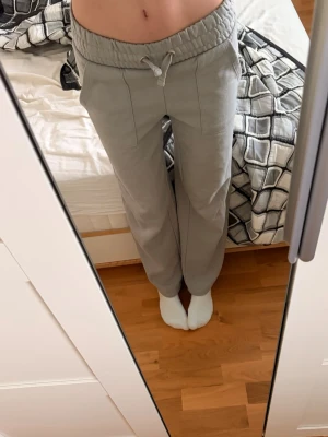 Grå mjukisbyxor från 157 - Säljer ett par ljusgrå mjukisbyxor från 157 i storlek XS. Byxorna har bred resårmidja med snörning, raka ben och stora fickor både fram och bak. Sköna och perfekta för chill dagar💞Innerbenslängd: 78cm      Waist: 70