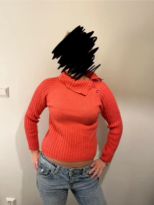 Ribbad orange polotröja med knappar - Säljer en ribbad orange polotröja med snygga knappar vid halsen. Tröjan har lång ärm och en lite croppad passform som sitter tajt. Köpte den i nyskick secondhand och det står ingen storlek, men skulle säga att det är storlek S. Skriv för fler bilder eller mått!🥰