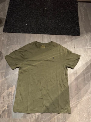 Ralph lauren T-shirt - Säljer en olivgrön t-shirt från Polo Ralph Lauren med klassisk passform och liten broderad logga på bröstet. Tillverkad i mjuk bomull och har rund halsringning samt korta ärmar. Perfekt