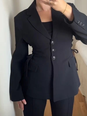 Gina Tricot side lacing shaped blazer 40 - Side lacing shaped blazer från Gina i storlek 40. Ny med prislapp. OBS Första bilden är inte min