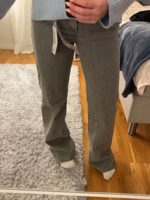 Ljusgrå jeans från NA-KD  - Helt nya och oanvända jeans från NA-KD. Prislapp finns kvar och ordinarie pris är 699kr. Jeansen är ljusgrå, storlek 34 och raka i modellen. 
