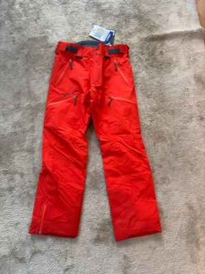 Röda skidbyxor från Stellar Equipment - Snygga vinter/skidbyxor från Stellar EQ. Dessa är stellar equipments nya Stellar EQ - Shell pants 2.0. Säljer pga fel färg och att retur perioden är över. Kommer med alla tillbehör och tags precis som ny. Kom gärna DM vid frågor. 