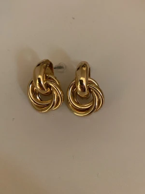 Örhängen  - Fina örhängen i guld färg. Ny skick! Liknar en knut. Super fina och ser lyxiga ut🩷🙏🏼