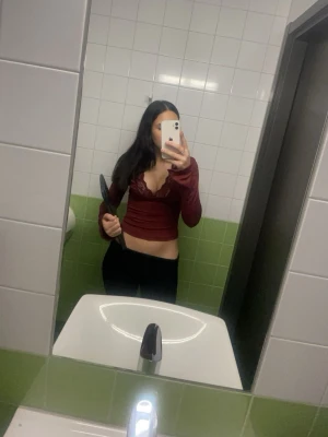 Vinröd croppad långärmad topp med spets - Säljer en vinröd croppad topp med långa ärmar och snygg v-ringning med spetsdetaljer. Toppen har en tight passform och är perfekt för dig som vill ha en trendig och feminin look. Materialet känns mjukt och stretchigt.