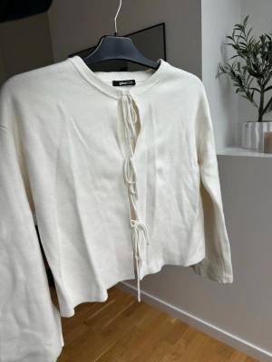 Vit kofta med snörning från Gina Tricot - Säljer en vit kofta från Gina Tricot i storlek XS. Koftan har långa ärmar, rund halsringning och snygg snörning framtill som detalj. Materialet känns mjukt och är stickat, perfekt för lager på lager under höst och vår.