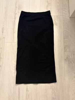 Svart långkjol från SHEIN - Enkel och stilren svart långkjol från SHEIN i storlek S. Kjolen har rak passform och är tillverkad i ett mjukt och stretchigt material som sitter snyggt på kroppen. Perfekt att matcha med en crop top eller oversized tröja.