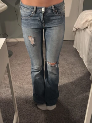 Blå bootcut jeans med hål - Säljer ett par ljusblå bootcut jeans med slitna detaljer på låret och knät. Från hm 💓