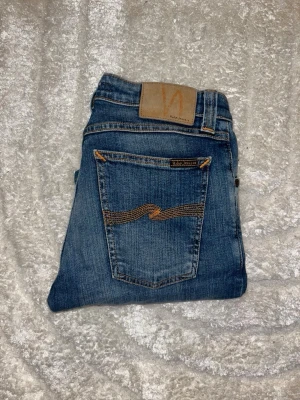 Nudie jeans  - Säljer dessa blåa jeans från nudie jeans, modell skinny lin. Midja 34cm, längd 92cm. JAG SKICKAR EJ FLER BILDER NÄR JAG BÄR JEANSEN! för bättre inblick i passformen rekommenderar jag att googla på modellnamnet. För storleksguide kolla måtten noggrant då JEANSEN KAN ALLTID VARA UPPSYDDA HELLER KEYMPA och jag ej tar emot returer :) s6,2
