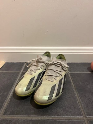  Adidas fotbollsskor - Säljer ett par Adidas fotbollsskor med klassiska svarta ränder på sidorna. Skorna har snörning och en låg profil, perfekt för dig som vill ha bra grepp på planen. Yttermaterialet är syntet och sulan är designad för att ge bra fäste.