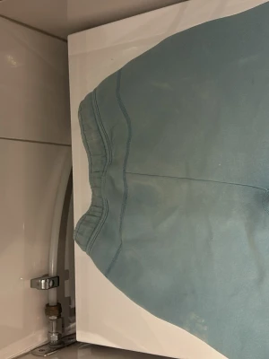 Ljusblå Nike shorts med snörning - Säljer ett par ljusblå Nike shorts med svart snörning i midjan och en svart detalj vid ena fickan. Shortsen har elastisk midja och är tillverkade i mjuk bomull, perfekta för chill dagar eller träning. Nike-logga broderad på vänster ben. Nypris är runt tusenlapp men pga användning säljer jag för endast 300!