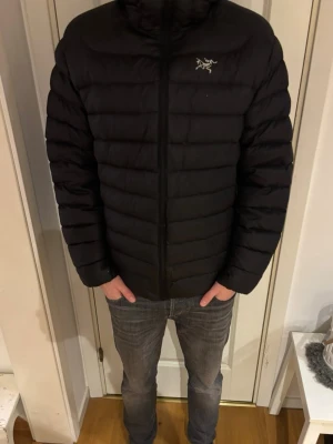 Svart pufferjacka från Arc'teryx - Säljer min brorsas svarta pufferjacka från Arc'teryx med broderad logga på bröstet. Jackan har horisontella sömmar, dragkedja framtill och hög krage. Perfekt för kyliga dagar och riktigt skön att bära. Klassisk och stilren design som funkar till det mesta. Den är i mycket fint skick och kostade ca 4000kr. Storlek M/L, säljer för 1999kr men priset går att diskutera!
