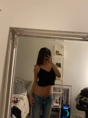 Svart croppad linnetopp från Zara - Säljer en svart croppad linnetopp från Zara med tunna axelband och v-ringad hals. Toppen är enkel och stilren, perfekt till jeans eller kjol. Materialet känns lätt och smidigt, vilket gör den skön att bära under varma dagar.