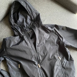 Blå vindjacka från J.Lindeberg stl L - Säljer en blå vindjacka från J.Lindeberg med huva.