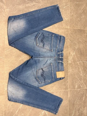 Replay anbass hyperflex W31/L32  - Ett par snygga anbass med en fin tvätt för en avslappnad look. Jeansen har små slitningar vid fickorna. De har även en slitning på Replay-märket, men annars inga defekter. Sitter som en smäck på benen och har en riktigt skön stretch som alla hyperflex har. Pris kan diskuteras.