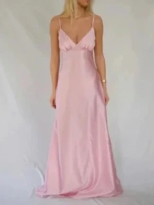 By Stina klänning strl M - Säljer en ljusrosa lång klänning i satin med smala axelband och v-ringning. Klänningen har en figurnära passform upptill och faller snyggt ner mot golvet. Perfekt för dig som gillar en romantisk och elegant stil.