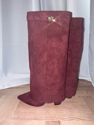 Vinröda mockastövlar med spänne - Snygga trendiga vinröda boots i mocka med dekorativt spänne upptill. Stövlarna har spetsig tå och låg klack, vilket ger en trendig och stilren look. Perfekta för att lyfta din outfit under höst, vår och vinter. Använd 1 gång 