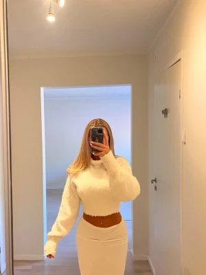 Vit fluffig cropped tröja - Säljer en vit, stickad, cropped tröja med långa ärmar och rund hals. Tröjan har en oversized passform och är gjord i ett mjukt, mysigt material. Passar storlek 32-36