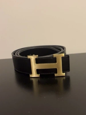 Svart guld H bälte  - Helt nytt bälte kommer plastat och skyddat mot repor. 110 cm långt 