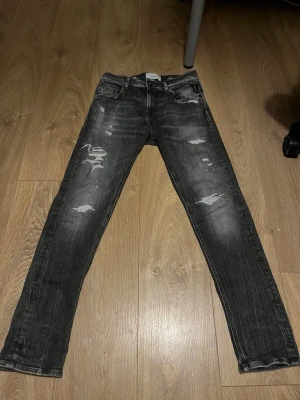 Svarta slitna skinny jeans - Snygga svarta skinny jeans med slitningar och distressed detaljer på framsidan. Jeansen har klassisk femficksdesign och en cool tvättad look. Perfekta för en trendig och avslappnad stil.