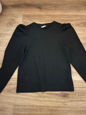 Svart långärmad topp med puffärm -  svart topp med långa ärmar och puffärmar vid axlarna. 