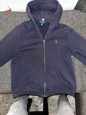 Ralph lauren kofta  - Tja säljer nu min Ralph lauren tröja som är använd men har tagit hand om den, har ett pittelitet hål i harmen och små fnaffs på ryggen går inte ens o få igen en penna! Annars väldigt fint skick bara höra av sig vid intresse eller frågor🙌 modellen är 175 o väger 65kg mvh Melwin☺️