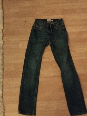 Mörkblå raka jeans - Snygga mörkblå jeans med rak passform och klassisk femficksdesign. Jeansen har knappgylf och bälteshällor, perfekta till en avslappnad stil. Tillverkade i slitstarkt denimtyg.