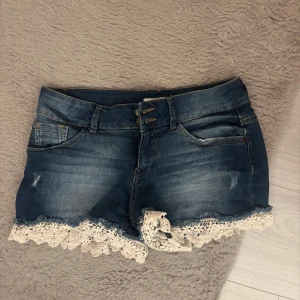 Blå jeansshorts med spetsdetalj - Svin snygga lågmidjade jeansshorts med vit spetskant, pris kan diskuteras💓