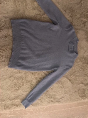 Cashmir kofta - säljer en fet Ljusblå tröja med rund hals och långa ärmar. Tröjan är stickad i ett mjukt material och har ribbade muddar vid ärmslut och nederkant. Enkel och stilren design som är lätt att matcha med olika outfits.