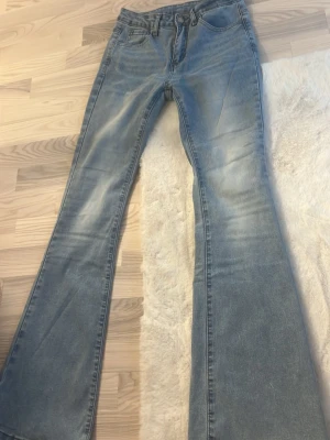 Ljusblå bootcut jeans - Säljer ett par ljusblå bootcut jeans med klassisk femficksmodell och utsvängda ben. Jeansen har en snygg tvättad look och är tillverkade i denim. Perfekta för dig som gillar retrostil och vill ha ett par riktigt schyssta jeans med breda ben.
