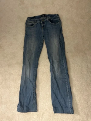 Blå bootcut jeans från ltb - Säljer ett par klassiska blå bootcut jeans från ltb med lätt slitningar framtill. Jeansen har normal midja, fem fickor och dragkedja med knapp. Perfekta för en avslappnad och trendig look.