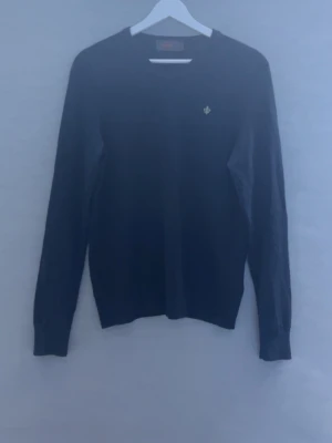 Mörkblå tröja (morris) - Klassisk mörkblå tröja från Morris med rund halsringning och diskret broderad logga på bröstet. Tröjan har långa ärmar och ribbade muddar vid ärmslut och nederkant. Perfekt för en stilren look.