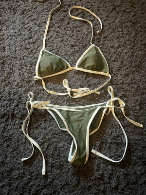 Olivgrön bikini med vita kanter XS - Aldrig använd bikini. Överdelen har väldigt små trianglar
