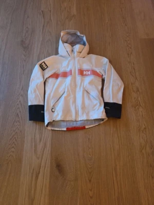 Vit vindjacka från Helly Hansen - Jättefin jacka från helly hansen i nyskick. Riktigt snygg och passar i alla väder😊