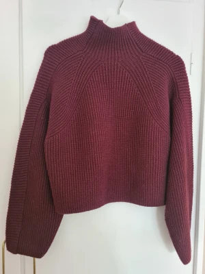Vinröd ribbstickad polotröja från H&M - Vinröd ribbstickad tröja med hög krage och långa ärmar. Tröjan har en boxy passform och stickade detaljer.