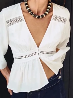 Vit blus med broderidetaljer - Trendig vit blus från ZARA med djup V-ringning och broderade detaljer längs bröst och midja. Blusen har trekvartsärm och lätt rynkad, luftig passform. Perfekt till jeans eller kjol för en fräsch look.