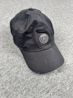 Svart PSG x Jordan keps - Snygg svart keps från Jordan i samarbete med Paris Saint-Germain. Klassisk böjd skärm, justerbart spänne bak och PSG-logga framtill. Tillverkad i bomull med ventilerande öljetter och diskret design som passar till streetwear.