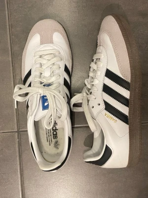 Adidas Samba vita och svart  - Jättesnygga adidas Samba OG sneakers i vitt läder med svarta ränder!! Säljer för att de var för små och sent att lämna tillbaka. 