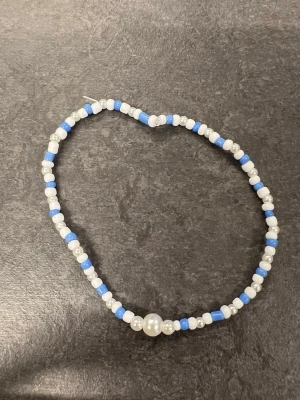 Pärlarmband med blå och vita pärlor storlek XL - Ett handgjort armband med vita och blå pärlor, samt en större vit pärla som detalj. 