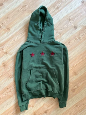 Peaceinwar ig brand hoodie - Grön hoodie med tre röda stjärnor broderade på bröstet. Har en stor huva, magficka och råa, fransiga kanter nedtill för en avslappnad look. Perfekt för dig som gillar streetwear och unika detaljer. Dm för mått