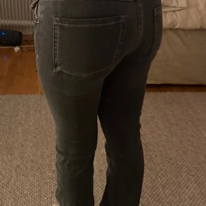 Svarta bootcut jeans med låg midja - Snygga svarta jeans med bootcut passform och låg midja. Klassisk femficksdesign med silverfärgade knappar och detaljer. Jeansen har en smalare passform upptill och lätt utsvängda ben. Perfekta för dig som gillar en cool och tidlös stil.