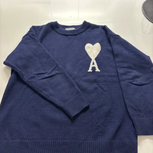 Mörkblå stickad tröja från Ami Paris - Säljer nu min stilrena Ami Paris sweatshirt i mycket bra skick, ingen defekt. Tag och påse ingår som ni ser på bild 3. Hör av er vid frågor!👊