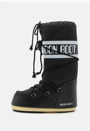 Svarta Moon Boots med snörning - Svarta Moon Boots med vit logga och snörning runt skaftet. Storlek 39-40. Skorna har en hög, vadderad design och platt sula i beige. Tillverkade i syntetmaterial och perfekta för kalla vinterdagar. Ikonisk retrostil med tydliga logodetaljer.